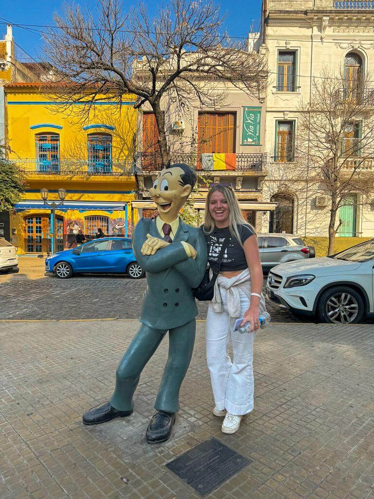 Me standing beside a statue of Mafalda in the colorful San Telmo neighborhood of Buenos Aires with bright historic buildings behind them. Popular photo stop connected to the famous Argentine comic character often included when exploring the city during a 2 days in Buenos Aires itinerary.