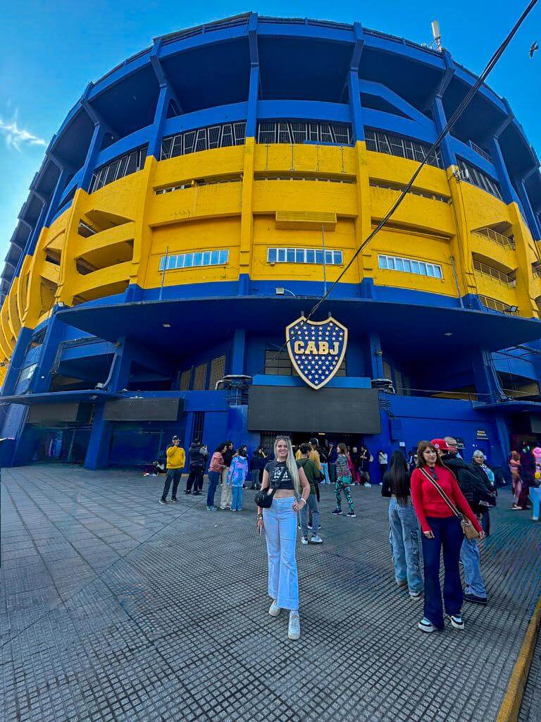 Exterior of La Bombonera stadium in Buenos Aires painted in bright blue and yellow with the Boca Juniors crest reading "CABJ" above the entrance. Visitors stand outside the iconic football stadium in the La Boca neighborhood, a popular stop during a 2 days in Buenos Aires itinerary.